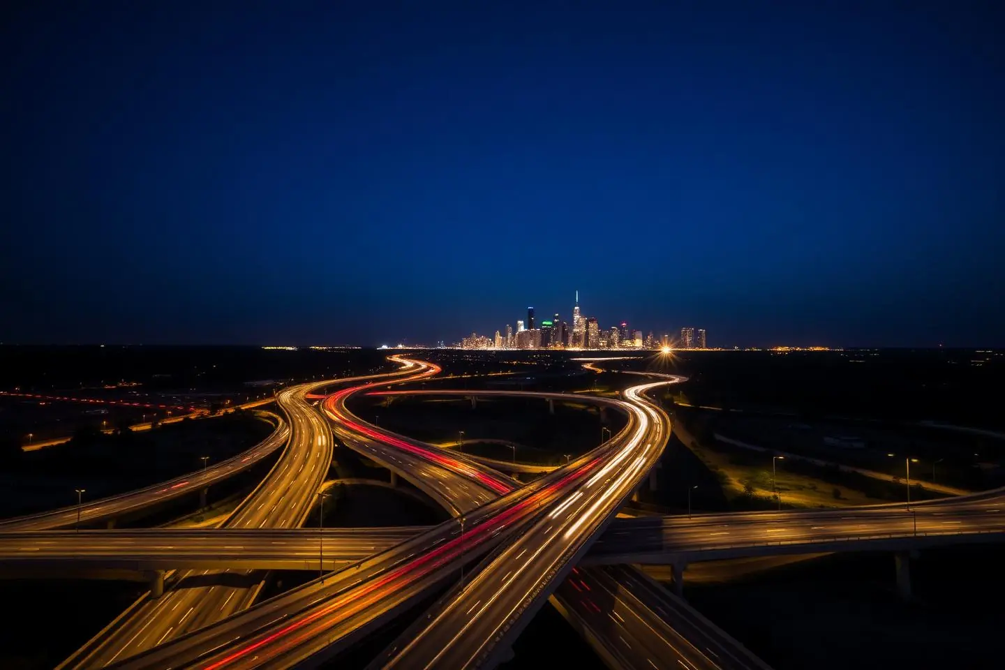 Highway interchange at night leading toward a distant city skyline